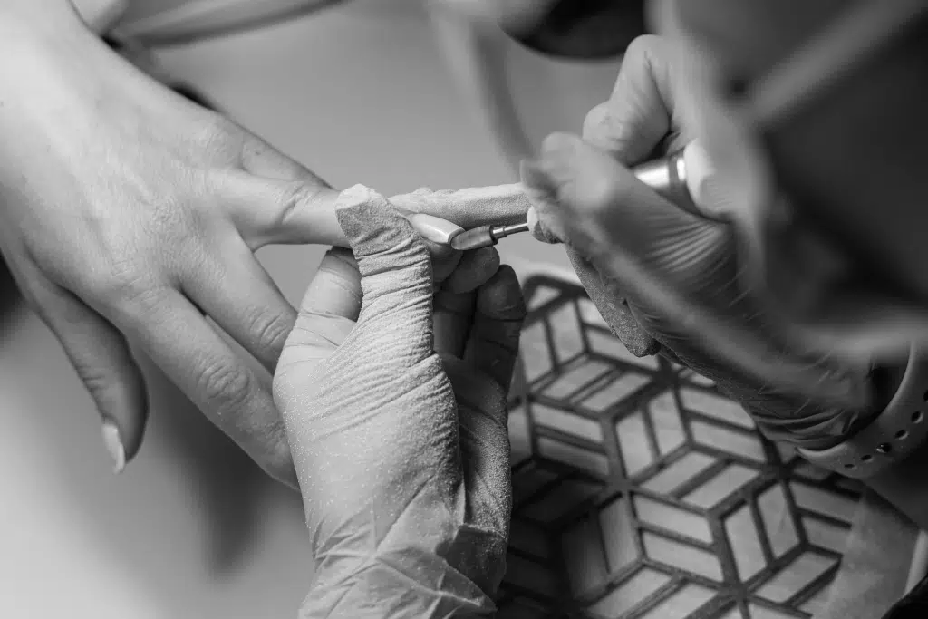 insured nail technician shaping client's nails